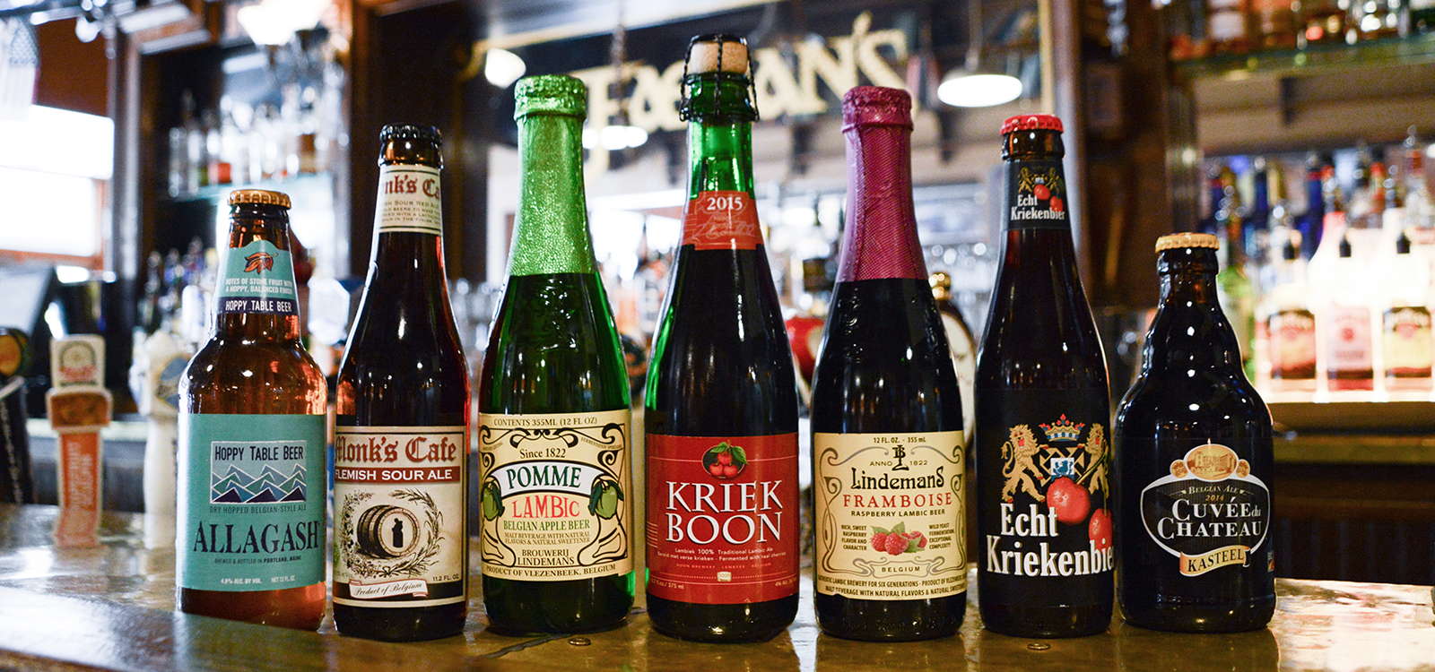 7 lambic beer bottles on a bar